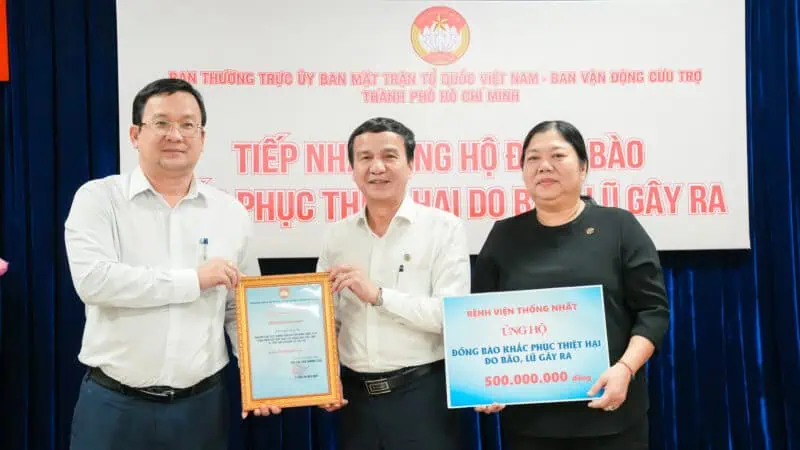 Hình ảnh các đại diện trao quỹ hỗ trợ tại buổi lễ, thể hiện sự đoàn kết và chia sẻ khó khăn với cộng đồng.